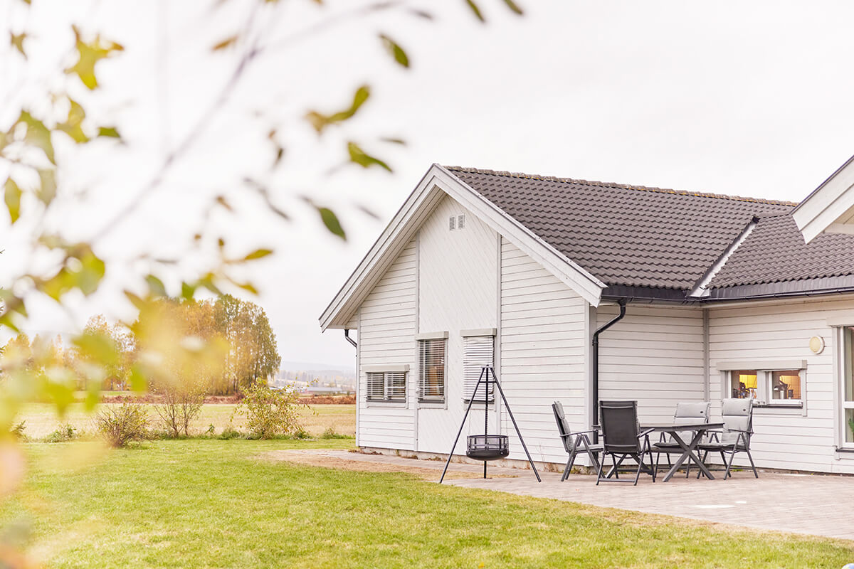 En hage med bålpanne og spiseplass, bak et hvitt hus