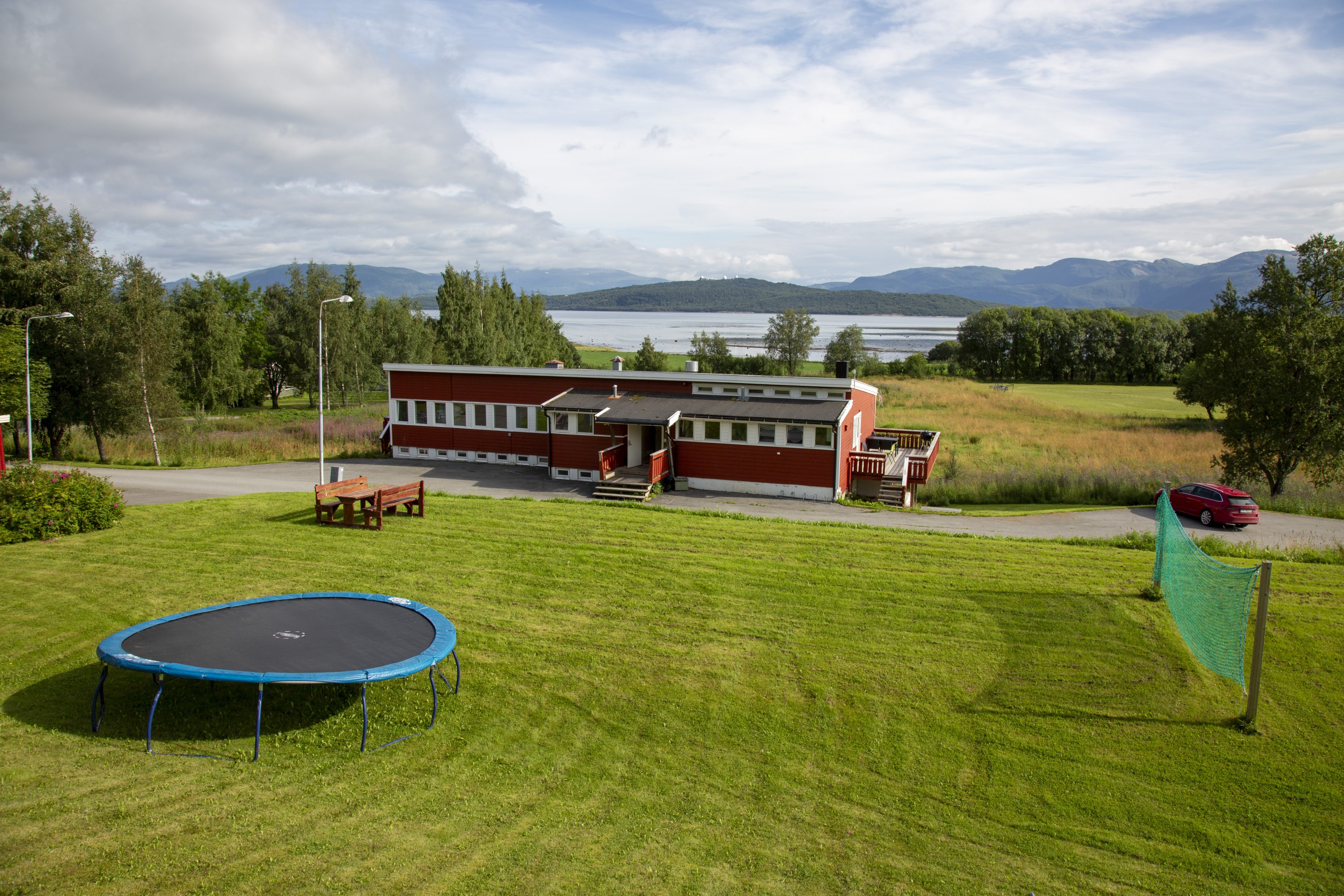 Bygning med plen, volleyballnett og trampoline